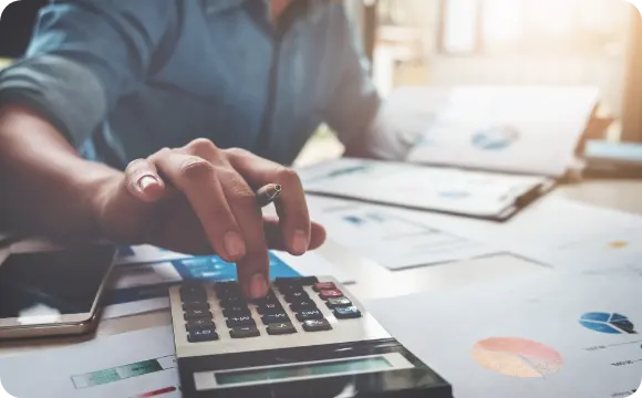photo of hands working a calculator while reviewing documents